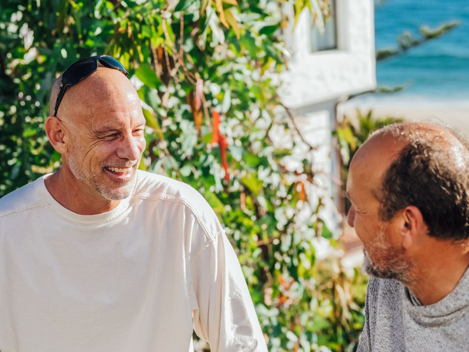 Two men sitting together in conversation outdoors in bright natural light